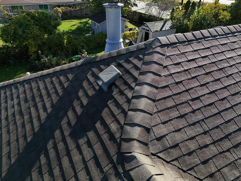 Close-up of worn asphalt shingles around a roof vent, a common leak spot
