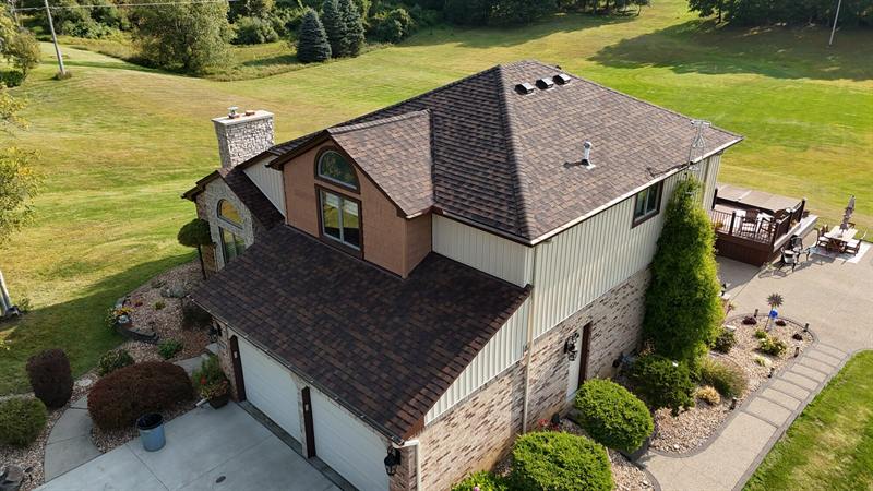 Two-story home with brown shingles and a stone chimney